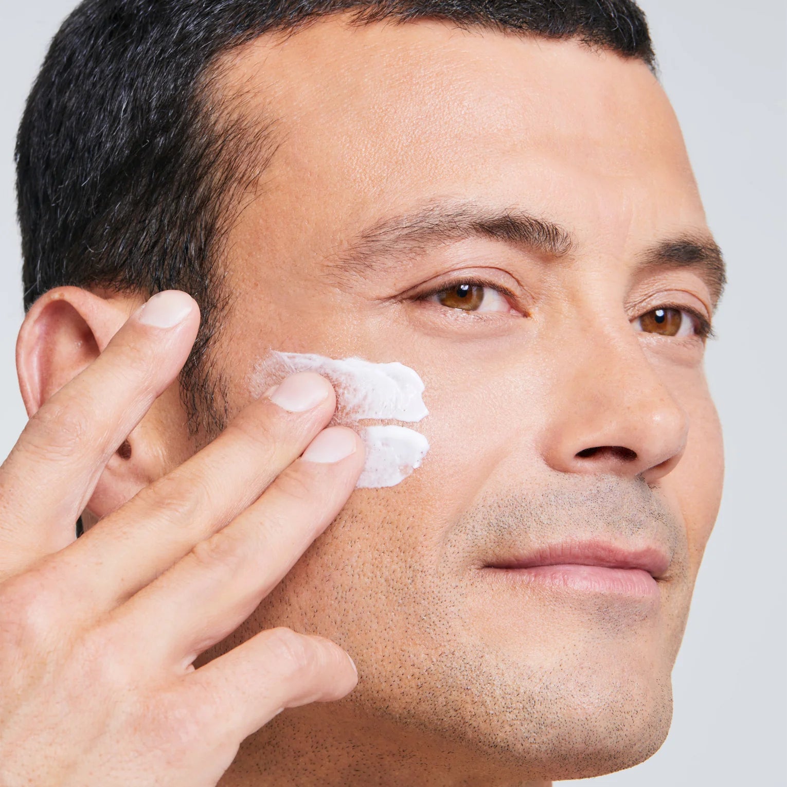 A man using Cellmen Face Ultra cream on his face, emphasizing a routine of skincare and self-care.