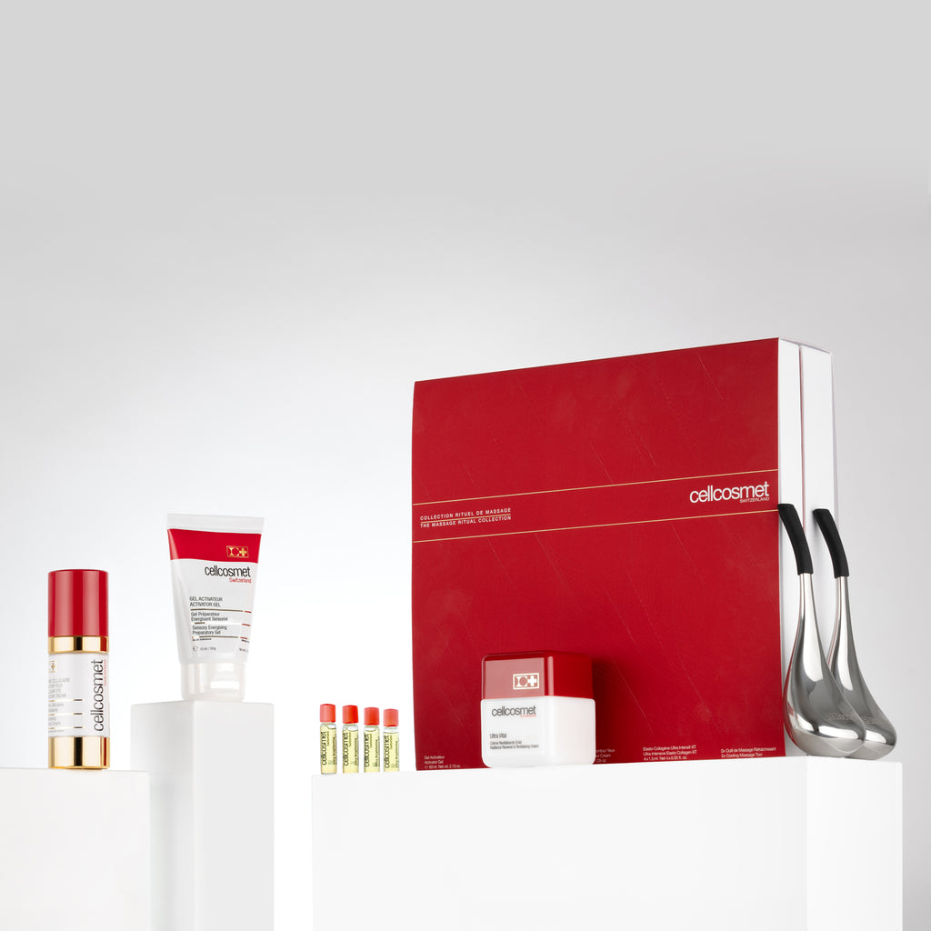 The Massage Ritual Collection skincare products arranged in a box on a white table, featuring creams and cryo-sticks for rejuvenation.